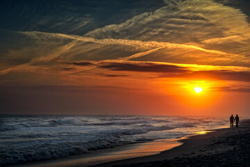 Fototapeta na wymiar romantic couple holding hands on the beach at sunset