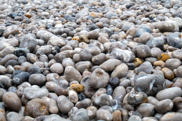Close up of the pebbles on a beach in Normandy France, creating an Abstract smooth round pebbles sea texture background 