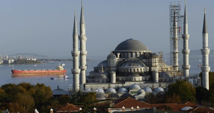 View of the Blue Mosque (Sultanahmet Camii) in Istanbul, Turkey with big cargo ship crossing the bosporus strait in background