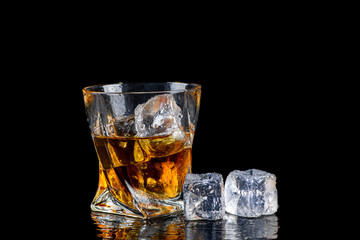 Glass of whiskey with cube ice on black background