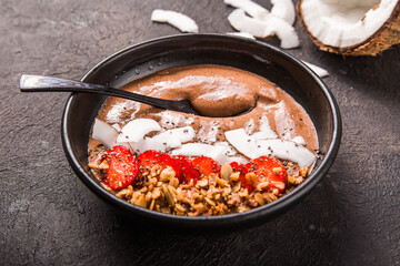 Healthy breakfast bowl. Chocolate banana smoothie bowl with coconut flakes, granola, strawberry.