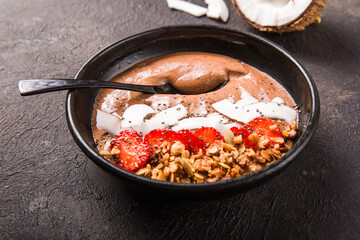 Healthy breakfast bowl. Chocolate banana smoothie bowl with coconut flakes, granola, strawberry. Top view, flat lay, overhead
