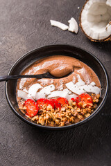 Healthy breakfast bowl. Chocolate banana smoothie bowl with coconut flakes, granola, strawberry. Top view, flat lay, overhead