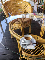 street view of a coffee terrace with table and chairs. hot coffee on a glass table