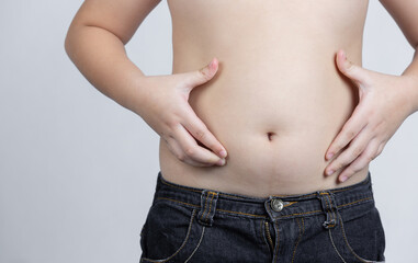 Naklejka premium hand holding excessive belly fat on gray background. concept of surgery and subcutaneous fat breakdown.