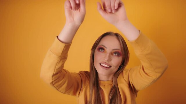 Beautiful gilr celebrating and dancing. Portrait and isolated on yellow background