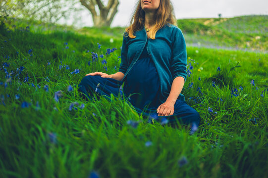 Pregnant woman relaxing in meadow of bluebells