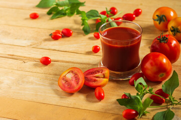 Tomato juice in clear glass On the wooden table Decorate with small and large fruits.