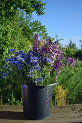 A large bouquet of wildflowers in a bucket.