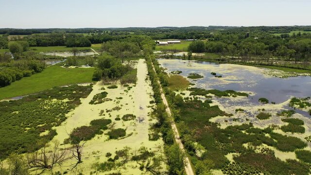 Aerial view of open water marsh and recreational trail through it. Midwestern landscape, wilderness from above. Daytime, summer