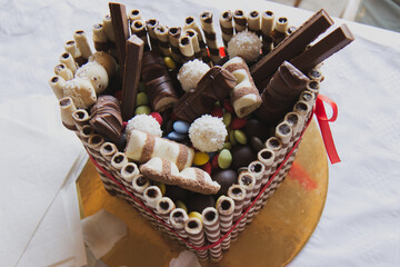 Sweet heart-shaped chocolate birthday cake with sweets on top as decoration, made up of chocolate filled tubes