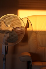 cooling by a fan in the summer heat while resting in an armchair