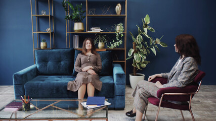 Young woman with closed eyes lying on sofa and listening psychologist at therapy session