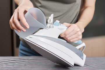 Woman load water in the iron. Prepare iron for ironing