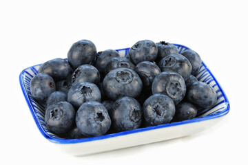 Fresh Blueberries in a blue and white dish, isolated on white with copy space.