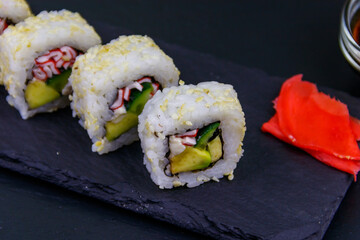 Uramaki sushi rolls with surimi on a black slate