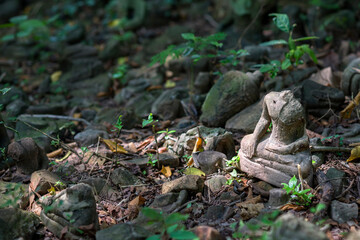 Ancient old damaged Buddha statue sculpture of stone were left statue in the forest ruin temple of Thailand