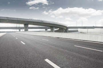 Clear blue sky and white clouds in the background, highway overpass curved approach bridge