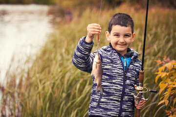 Cute boy catches fish on a summer lake. Activity in nature fishing. Happy childhood