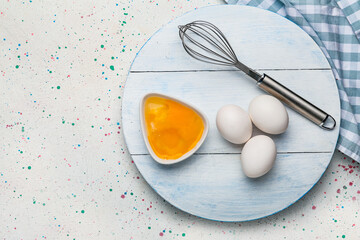 Fresh chicken eggs and whisk on table