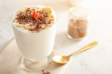 Glass of yogurt with fruits and flax seeds on light background