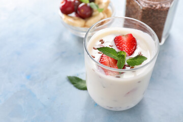 Glass of yogurt with strawberry and flax seeds on color background