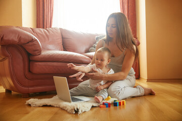 Mother and little baby playing on floor at home