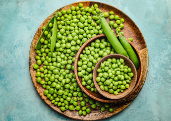 Plate and bowls with tasty fresh peas on color background