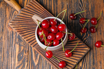 Cup with sweet cherry on table