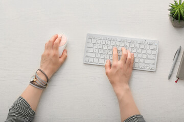Woman using PC mouse while working on computer at table, top view