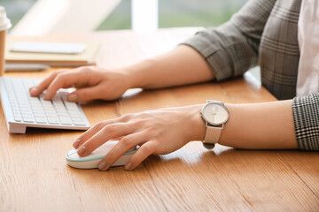Woman using PC mouse while working on computer at table, closeup