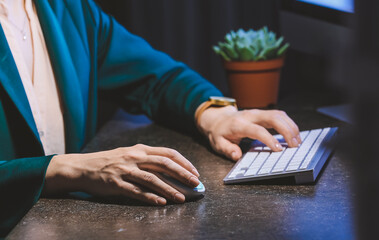 Woman using PC mouse while working on computer at table, closeup