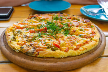 Pizza with cherry tomatoes and dry basil on the wooden white plate