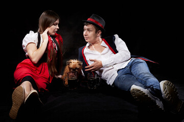 Happy Oktoberfest couple in national ethnic dress with mug of beer, small shaggy dog resting on...