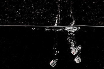 Ludo dice in water splash on black background with lots of air bubbles
