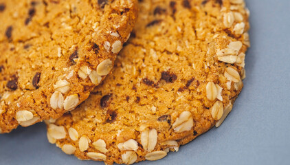 Close up detail of two golden color oatcakes with chocolate chips and nuts, stacked and placed on a blue grey breakfast plate. Shallow depth of field.   