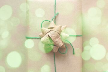 present wrapped in plain recycled paper with green thread on beige background
