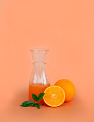 Orange juice in the glass jar with fresh orange on orange color background.