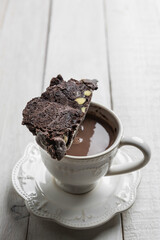 Chocolate biscotti or cantuccini over a hot chocolate mug, on a rustic white wooden table with copy space.