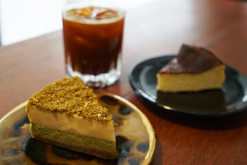 Close up Basque burnt and Matcha green tea cheesecake served with iced black coffee