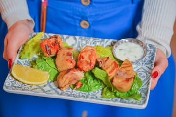 Waiter serves grilled chicken meat with salad and sauce. Healthy dinner. Eating out in restaurant.