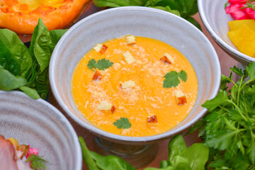 A bowl of spicy pumpkin soup, swirled with coconut cream.