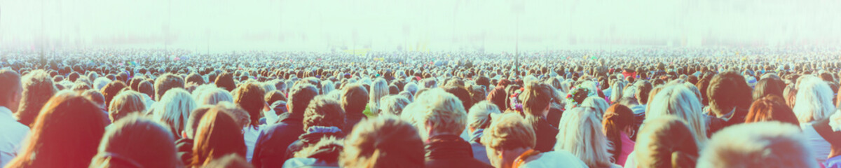 Panoramic photo of large crowd of people. Slow shutter speed motion blur. Artistic filters aplied