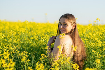 Beautiful girl in a rapeseed field, with an open shoulder.