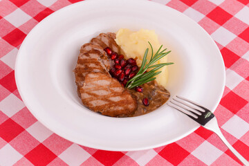 Grilled steak seasoned with salt and herbs. Served with mashed potatoes and pomegranate seeds.