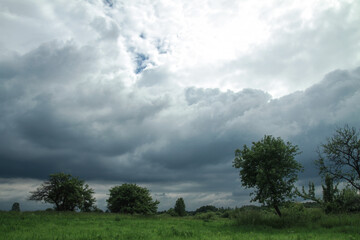 Thunderous epic clouds in a field near the old garden. Stock photo background with heaven.