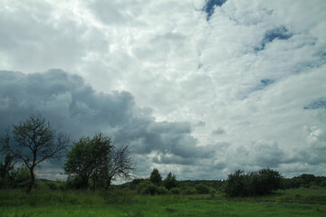 Thunderous epic clouds in a field near the old garden. Stock photo background with heaven.