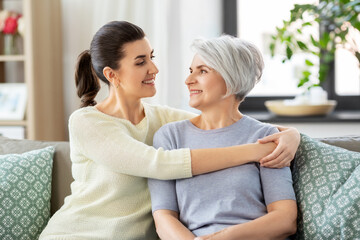 family, generation and people concept - happy smiling senior mother with adult daughter hugging at home