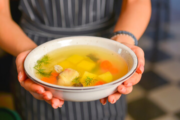 A waiter wearing black uniform serving a bowl of hot soup in a restaurant. Concept for a tasty and healthy meal.