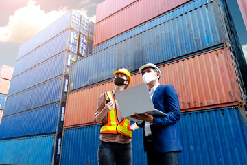Teamwork foreman man and woman wearing protection face mask and safety helmet using laptop and radio communication checking containers in cargo ship, Industrial container cargo concept.